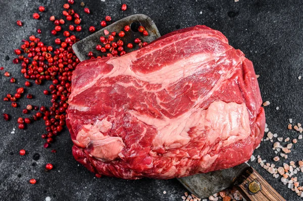 Raw Chuck eye roll steak on meat cleaver. Organic beef. Black background. Top view.