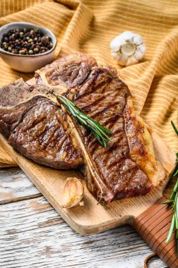 Doğrama tahtasında ızgara biftek. Pişmiş et. Beyaz ahşap arka plan. Üst görünüm.