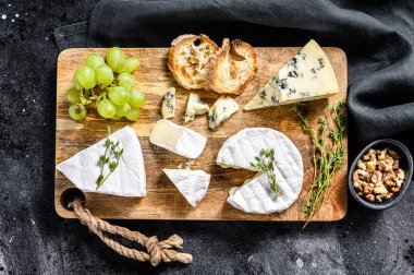 Fransız peynirli peynir panosu, peynir ve mavi peynir, üzüm ve ceviz. Siyah arka plan. Üst görünüm.