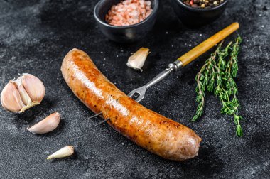 Et çatalında baharat ve otlarla ızgara domuz sosisi. Üst Manzara. Siyah arkaplan.