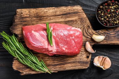 Tahta kesme tahtasında taze çiğ sığır filetosu bifteği. Siyah ahşap arka plan. Üst görünüm.