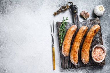 Ahşap kesme tahtasının üzerinde baharat ve otlarla kızartılmış sosisler. Üst Manzara. Beyaz arka plan. Boşluğu kopyala.
