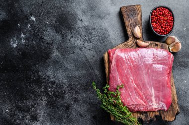 Tahta kesme tahtasının üzerinde çiğ kanat ya da biftek. Siyah arka plan. Üst Manzara. Boşluğu kopyala.