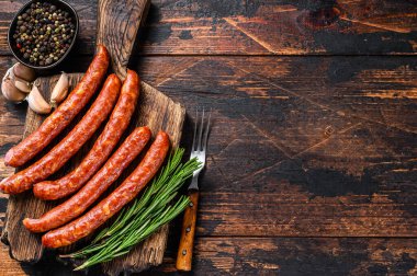 Taze aromatik otlar ve baharatlarla birlikte sıcak füme sosis. Koyu ahşap arka plan. Üst Manzara. Boşluğu kopyala.