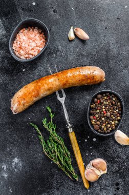 Et çatalında baharat ve otlarla kızartılmış sosis ızgarası. Üst Manzara. Siyah arkaplan.