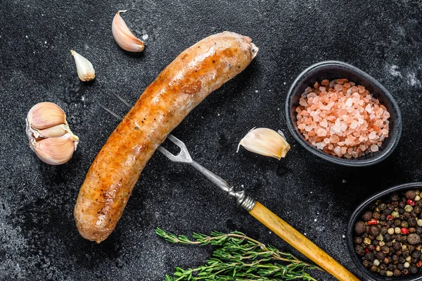 Et çatalında baharat ve otlarla ızgara domuz sosisi. Üst Manzara. Siyah arkaplan.