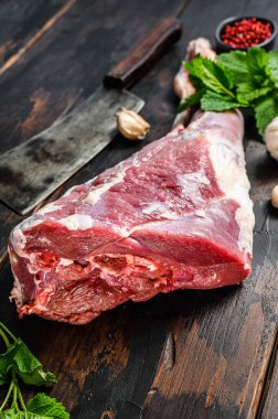 Bitki ve baharatla dolu çiğ keçi bacağı. Çiftlik eti. Koyu ahşap arka plan. Üst görünüm.