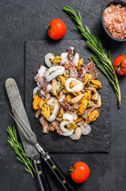 Çeşitli deniz ürünleri, midye, istiridye, mürekkep balığı, ahtapot, karides ve karides. Siyah arka plan. Üst görünüm.