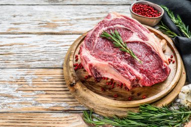 Kemiğe pirzola ya da kovboy bifteği. Çiğ Dallas bifteği. Beyaz ahşap arka plan. Üst Manzara. Boşluğu kopyala.