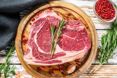 Kemiğe pirzola ya da kovboy bifteği. Çiğ Dallas bifteği. Beyaz ahşap arka plan. Üst görünüm.