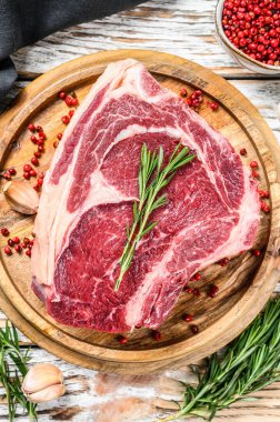 Çiğ kovboy bifteği ya da kemik üzerinde pirzola. Mermer biftek. Beyaz ahşap arka plan. Üst görünüm