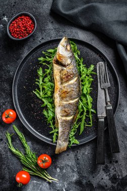 BBQ deniz levreği, roka ve kızarmış levrek. Siyah arka plan. Üst görünüm.