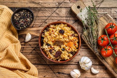 Pirinç pilavı, kuzu eti ve sebzeli ahşap bir kasede. Ahşap arka plan. Üst görünüm.