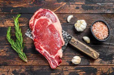 Çiğ kovboy ya da et satırının kemiğinde pirzola. Mermer biftekli pirzola. Koyu ahşap arka plan. Üst görünüm.
