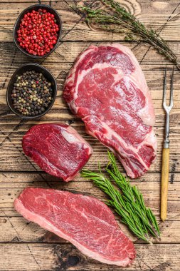 Taze çiğ siyah angus bifteği fileto Mignon, pirzola ya da kovboy, Striploin. Ahşap arka plan. Üst görünüm.
