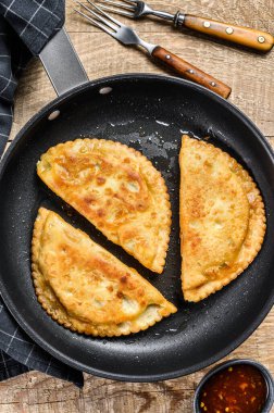 Kızarmış börek, tavada sığır eti dolgulu lezzetli hamur işleri. Ahşap arka plan. Üst görünüm