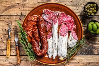 İspanyol şarküteri, dilimlenmiş sosis salam, fuet ve domuz sucuğu kırsal bir tabakta. Ahşap arka plan. Üst görünüm