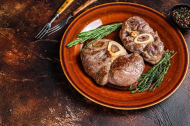 Kemikte pişmiş et, Osso Buco dana inciği, İtalyan ossobuco bifteği. Koyu ahşap arka plan. Üst Manzara. Boşluğu kopyala