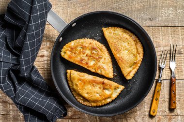 Etli ve otlu ev yapımı cheburekler, geleneksel Kafkas mutfağı. Ahşap arka plan. Üst görünüm