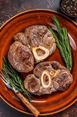 Kemikte pişmiş et, Osso Buco dana inciği, İtalyan ossobuco bifteği. Koyu ahşap arka plan. Üst görünüm