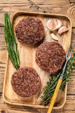 Barbekü ızgara biftek köfteleri, ahşap tepside kıyma. Ahşap arka plan. Üst görünüm