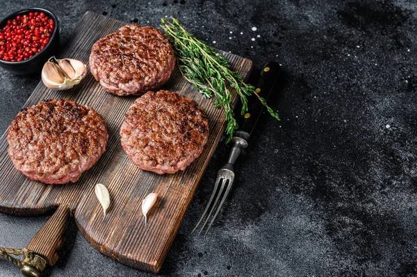 Hamburger için ızgara biftek köftesi kıyma ve ahşap bir tahtanın üzerinde otlar. Siyah arka plan. Üst Manzara. Boşluğu kopyala — Stok fotoğraf