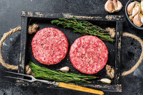 Hamburger için çiğ et köftesi, kıyma ve ahşap bir tahtanın üzerinde bulunan otlardan. Siyah arka plan. Üst görünüm — Stok fotoğraf