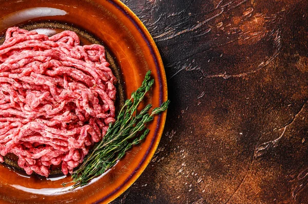 Angosce crude di carne macinata di manzo wagyu, carne macinata con erbe su un piatto. Sfondo scuro. Vista dall'alto. Copia spazio — Foto Stock