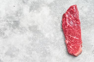 Çiğ Striploin bifteği, mermer biftek. Gri arka plan. Üst Manzara. Boşluğu kopyala.