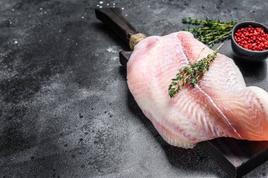 Kesme tahtasındaki çiğ balık filetosu. Siyah arka plan. Üst Manzara. Boşluğu kopyala.