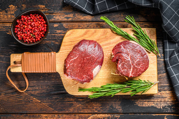 Raw fresh marbled meat Steak fillet mignon on a cutting board. Dark Wooden background. Top view.