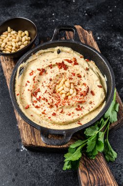 Hummus paste with chickpea and parsley in a bowl. Black background. Top view. clipart