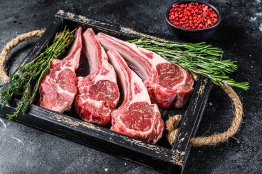 Çiğ kuzu eti, ahşap tepside biftek. Siyah arka plan. Üst görünüm.