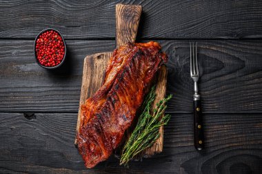 bbq soslu dana etinde ızgara. Tahta kesme tahtasının üzerinde kaburga eti. Siyah ahşap arka plan. Üst görünüm.