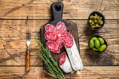 Tahta kesme tahtasının üzerinde ince dilimlenmiş salam salçamı. Ahşap arka plan. Üst görünüm.