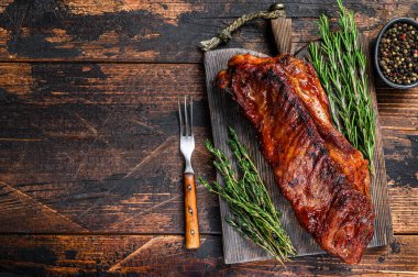 BBQ ızgara dana eti, ahşap kesme tahtasının üzerinde kaburga eti. Koyu ahşap arka plan. Üst Manzara. Boşluğu kopyala.