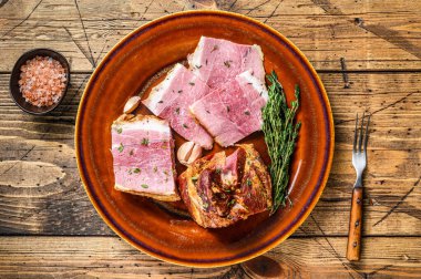 Kırsal bir tabakta domuz pastırması dilimleri. Ahşap arka plan. Üst görünüm.