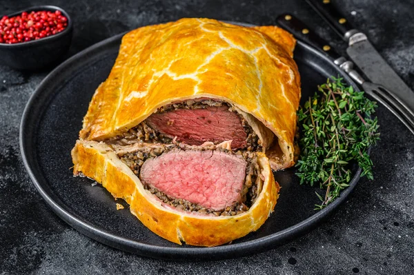 Wellington usulü biftek tabağında fileto eti. Siyah arka plan. Üst görünüm.