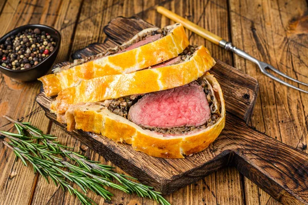 Sliced Beef Wellington pastry on a wooden cutting board. wooden background. Top view.