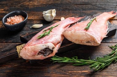 Taze taze kırmızı levrek ya da deniz kabuğu balığı. Koyu ahşap arka plan. Üst görünüm.