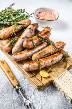 Kesme tahtasında ızgara sosis ve şifalı bitkiler. Beyaz arka plan. Üst görünüm.