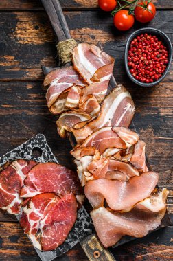 Et pancarı, pancetta, salam, dilimlenmiş jambon, sosis, jambon, jambon. Karanlık ahşap arka plan. Üst görünüm.