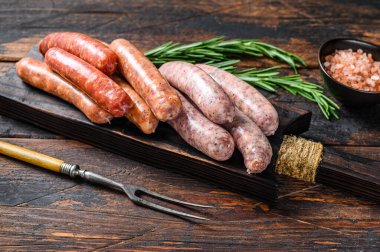 Kesme tahtasındaki çiğ sosisler. Koyu ahşap arka plan. Üst görünüm.