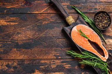 Çiğ somon bifteği kesim tahtasında pişirmek için hazırlandı. Koyu ahşap arka plan. Üst Manzara. Boşluğu kopyala.