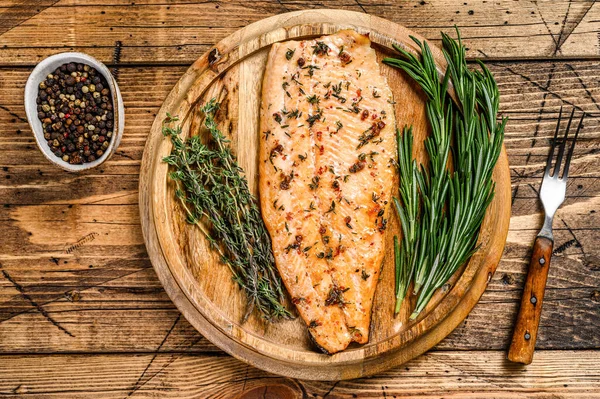 Cooked salmon fillet with herbs and pink pepper. wooden background. Top view.