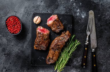 Misket tahtasında barbekü soslu ızgara biftek. Siyah arka plan. Üst görünüm.