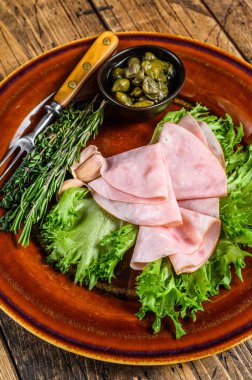 Taze salata ve kapari ile dilimlenmiş füme jambon. Ahşap arka plan. Üst görünüm.