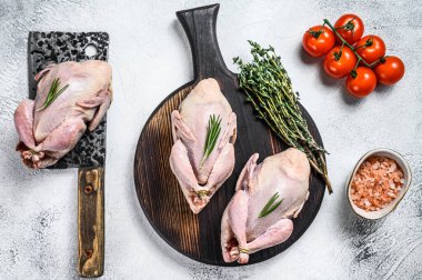 Çiğ bıldırcın hazırlama tahtasında et satırıyla. Beyaz arka plan. Üst görünüm