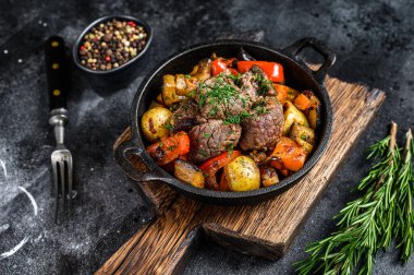 Koyu kırsal kesim tahtasındaki tencerede et güveci. Siyah arka plan. Üst görünüm