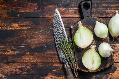 Tahta kesme tahtasındaki çiğ beyaz soğan. Karanlık ahşap arka plan. Üst Manzara. Boşluğu kopyala